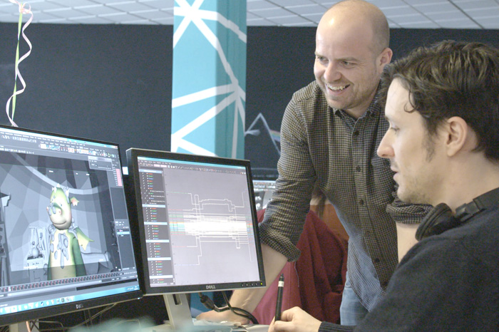 two men looking at computer graphic workstation on two screens